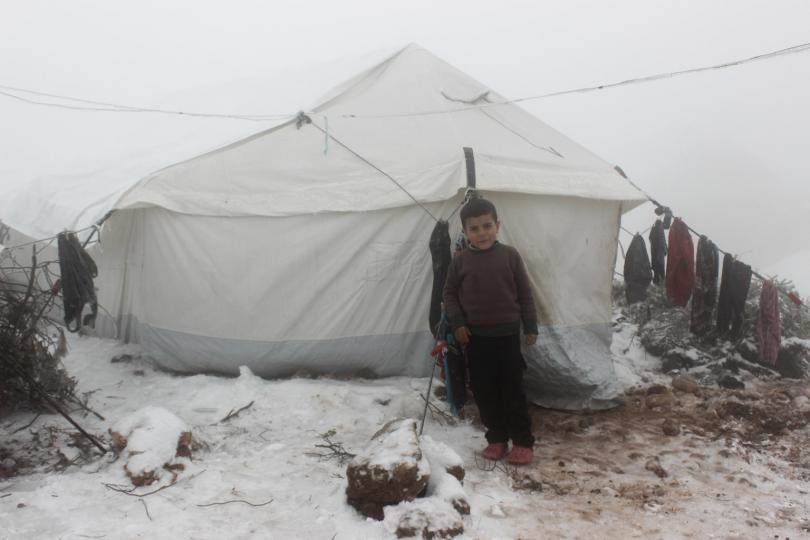 Þessi ungi drengur stendur við tjald fjölskyldu sinnar sem er á vergangi vegna átaka í Sýrlandi. Veturinn er kominn eins og sjá má. © UNICEF/Alshami - mynd